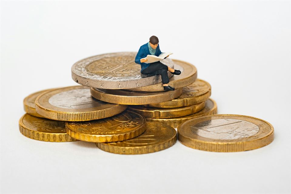 muñeco-pequeño-subido-encima-monedas-euro