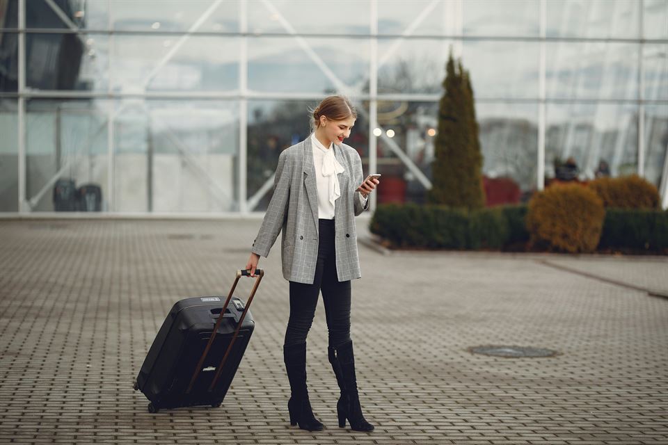 mujer-mira-movil-con-maleta-en-aeropuerto