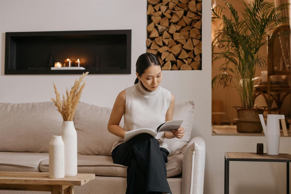 mujer-lee-revista-sentada-sofa-velas-aromaticas-al-fondo-marketing-olfativo-en-tu-vivienda-vacacional