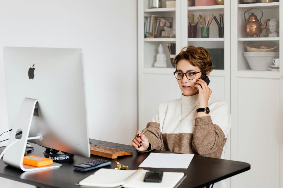 mujer-habla-por-telefono-sentada-delante-ordenador